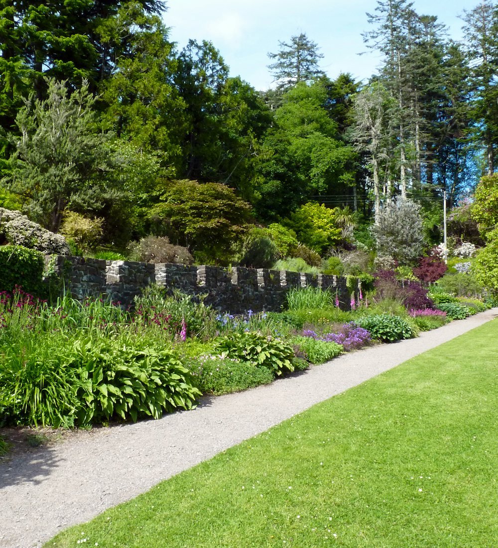 A mown lawn beside a gravel path and a deep planted border